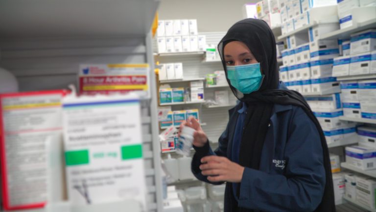 A Henry Ford Early College student works in the back room of a pharmacy.