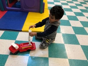 Indoor recess, one boy plays with a fire engine.