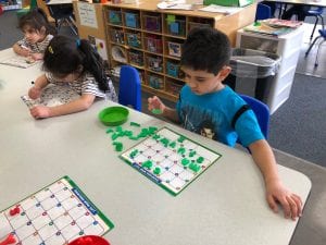 A preschool boy places magnetic letters into the correct boxes of an alphabetic chart.