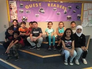 4th grade Miller students sit in front of the guest readers bulletin board at Cotter.
