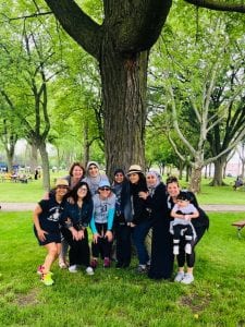 Students and teachers pose next to a tree at the park during their picnic.