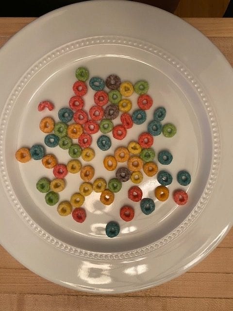 A white plate with multiple color fruit loops on the plate
