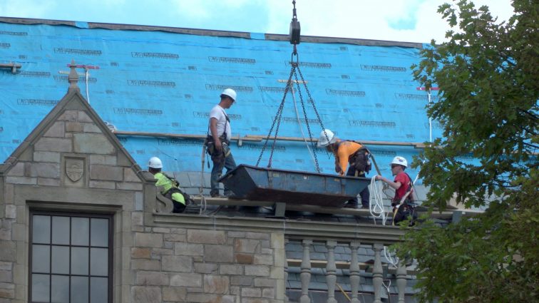 Workers replace the slate tile roof at Fordson High School
