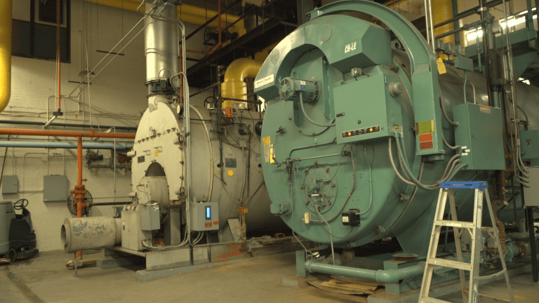 Two large, old boilers set in the Lowrey School boiler room. Only one boiler is working.
