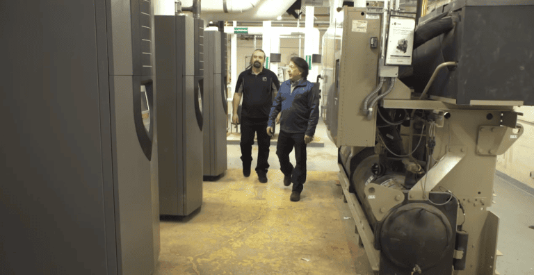 Two men walk through a modern school boiler room