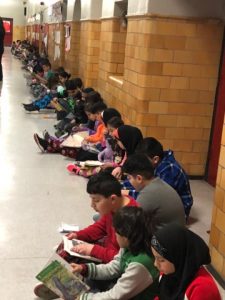 Row of students reading in the hallway