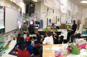 Superintendent Dr. Maleyko reading a book to students while students are on the carpet and Mrs. Younes and Mrs. Dillon are also in attendance. 