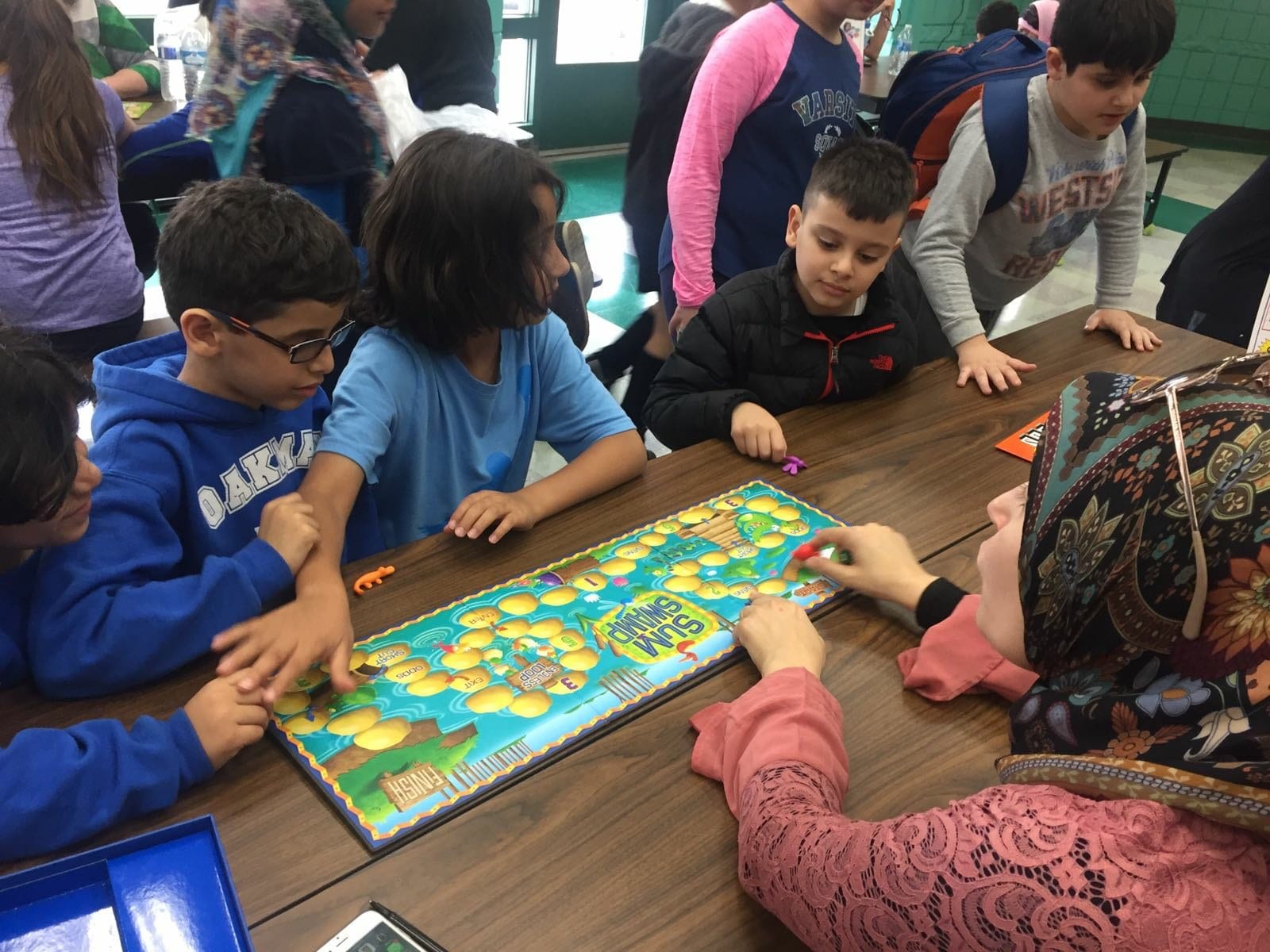 Students playing a math board game with Mrs. Awada