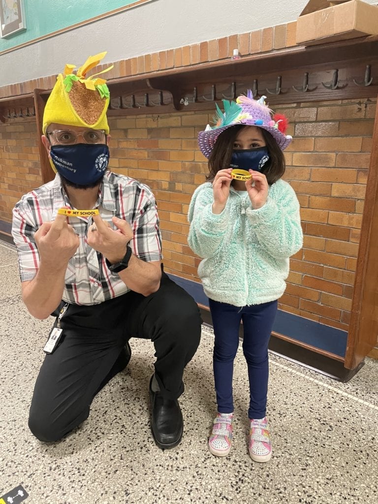 Mr. Abu-Rus and Hoda wearing silly hats and holding bracelets "I love my School" 