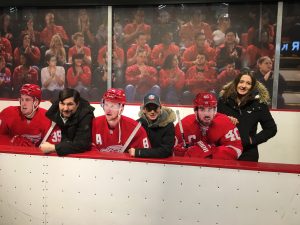At Caesars arena people sitting on a hockey bench with popup redwing figures. 