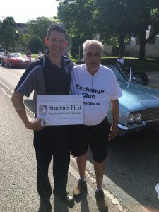 Adults with the student first sign at the memorial day parade. 