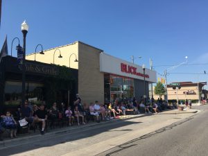 people sitting on the sidewalk watching the parade. 