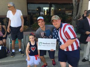 Students first sign and 2 adults and a child at the parade. 