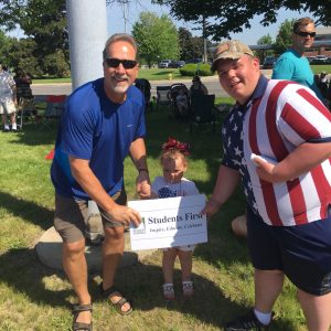 2 adults, a student, the sign and a selfie at the parade. 