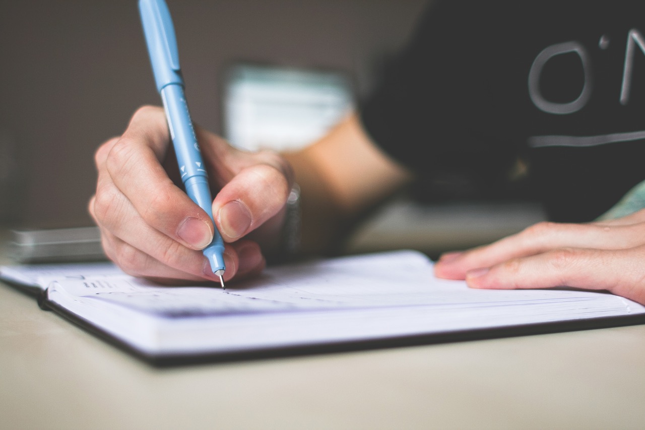 person writing with blue pen