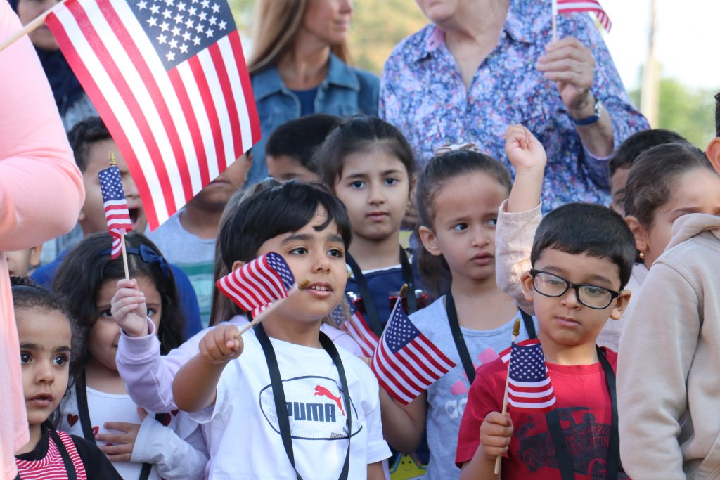 Young students wave American flags.