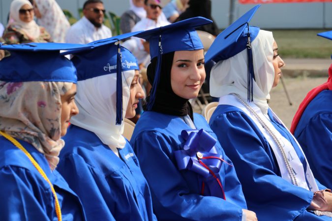 Students in caps and gowns sit during the Virtual K-12 graduation ceremony in June 2023.