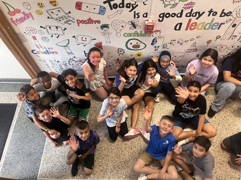 A group of students in front of a mural they are creating at Lindbergh Elementary as part of the 2024 Summer Discovery Program.