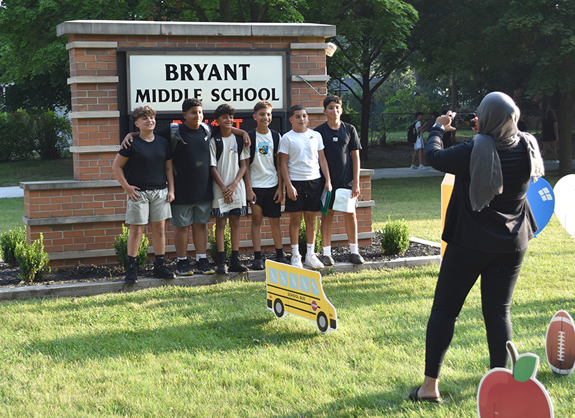 A group of students poses in front of the Bryant Middle School sign on the first day of school in August 2025.