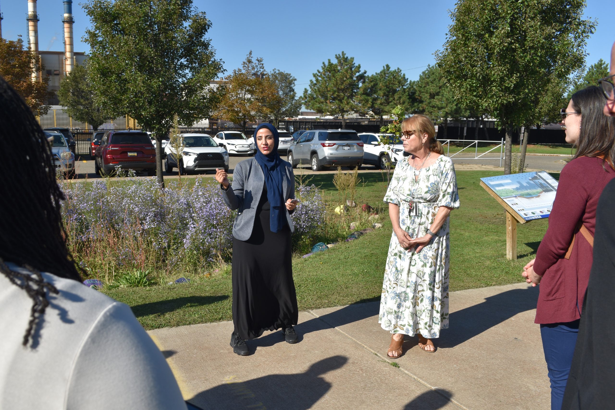 Salina Intermediate Principal Eman Ali stands with Elementary Principal Sue Stanley talking to guests in front of a flowering rain garden on the campus.