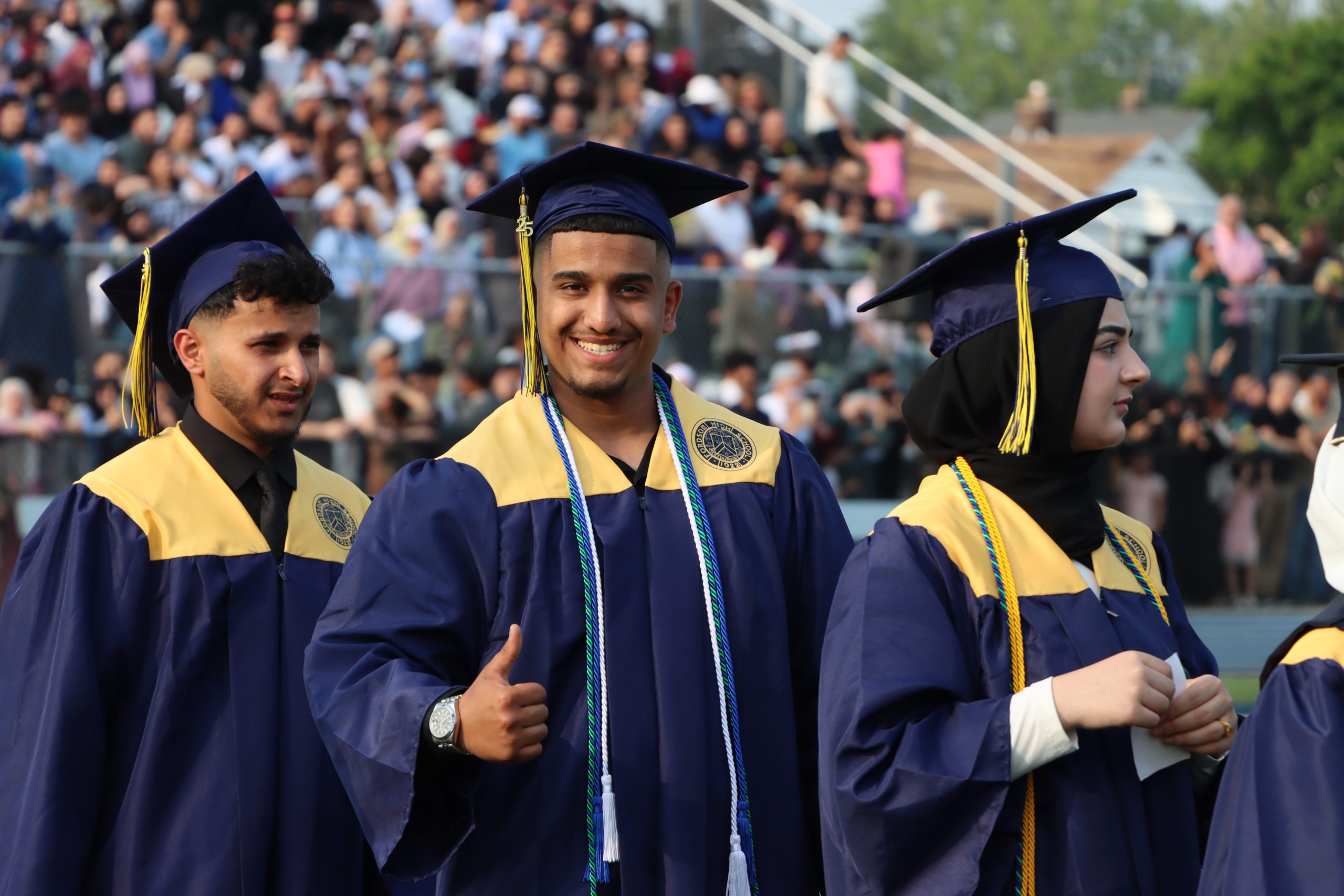 A student gives a thumbs up while standing in line at the 2025 Fordson High School graduation.