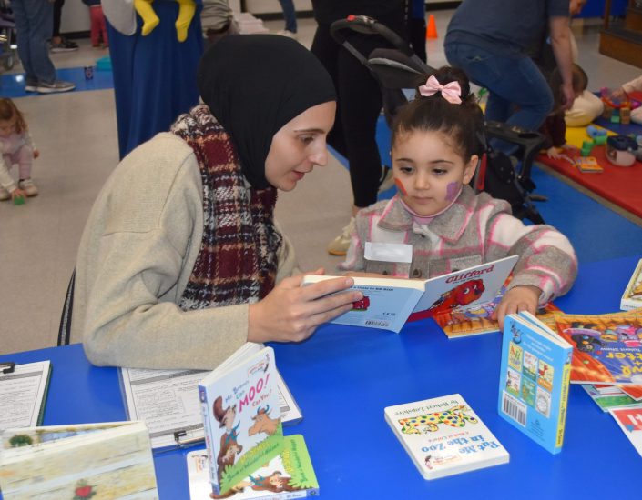 A woman reads a book to a young child during a Parent University session.