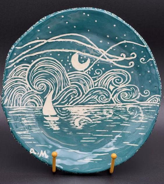 A handmade ceramic plate with an ocean and star lit sky