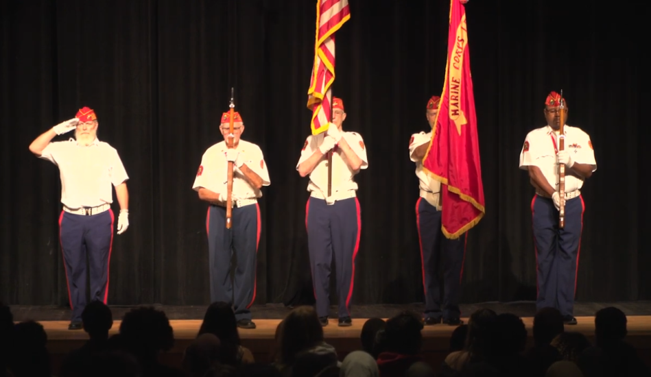 Veterans perform a flag presentation on stage during a Memorial Day ceremony