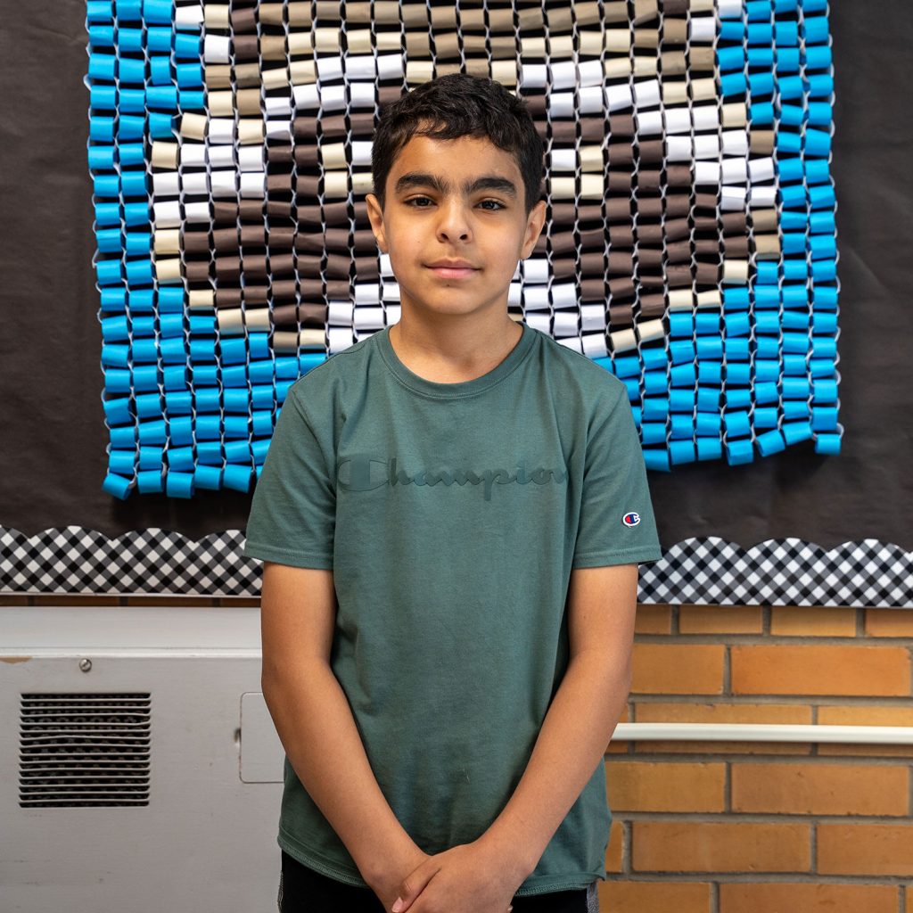5th grade student posing in elementary school hallway and smiling.