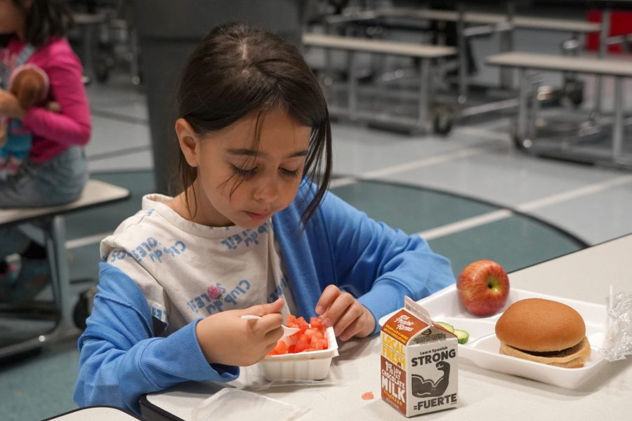 A student eats fresh fruit from a cup during a school lunch