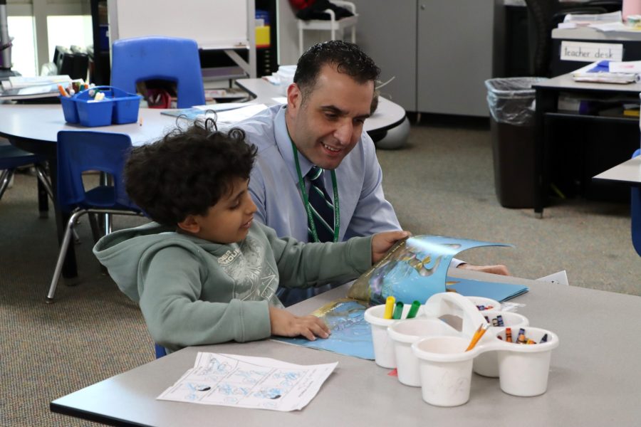 Mike Esseily looks at a book with a young child