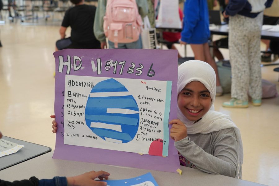 A student shows off a poster about a planet.