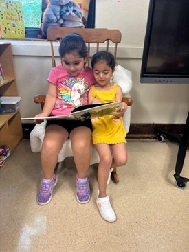 Two young students read together in a rocking chair.