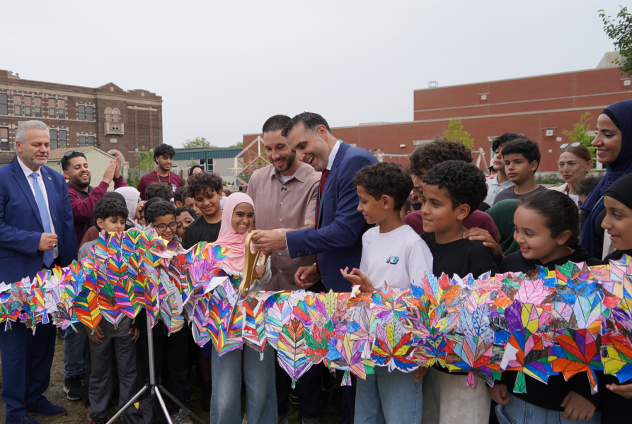 Mayor Abdullah Hammoud and Superintendent Mike Esseily with students and other officials cut a ribbon opening a new playground