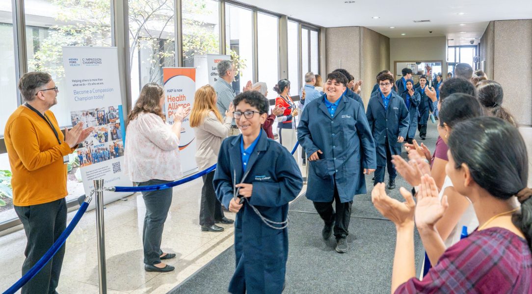 Adults clap as students in the Henry Ford Early College enter the Henry Ford Health System building for the first time for the 2026-27 school year